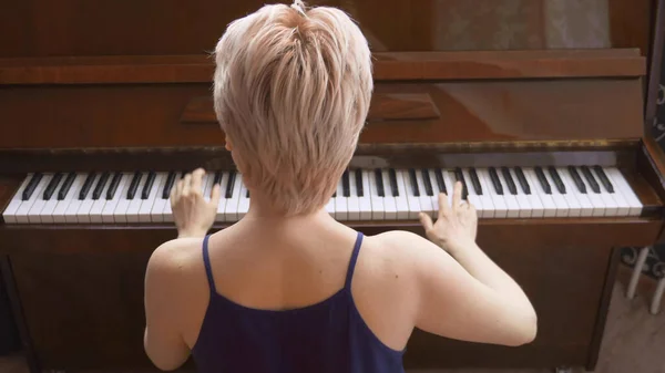 Visão traseira, loira frágil com cabelo curto toca piano — Fotografia de Stock