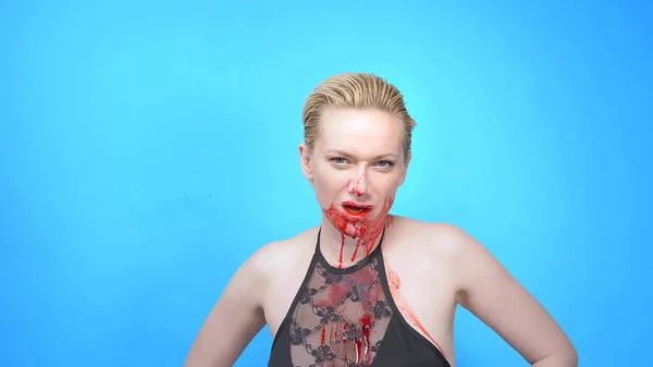 Mulher bonita com um rosto sangrando em um fundo azul. espaço de cópia — Fotografia de Stock