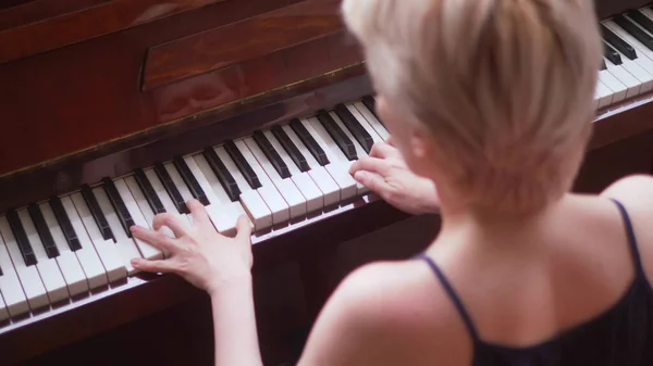 Rear view, fragile blonde with short hair plays the piano Stock Image