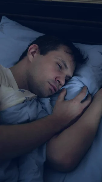 Bovenaanzicht. Een close-up. Jongeman in bed lijdt aan slapeloosheid. verticaal — Stockfoto