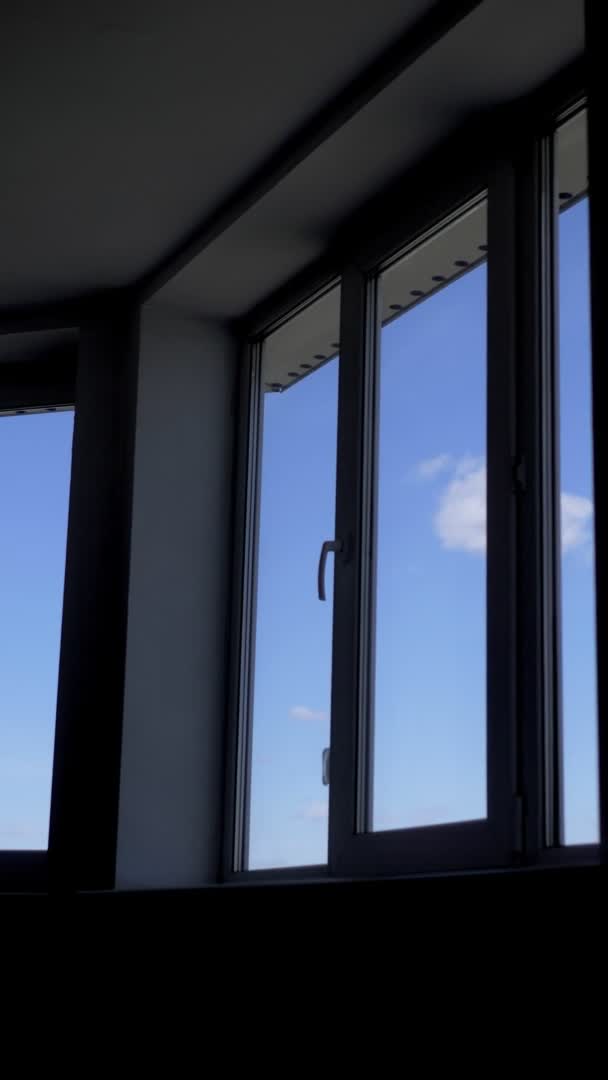 Verticalmente. la vista desde la ventana del apartamento en el cielo azul con nubes blancas — Vídeos de Stock