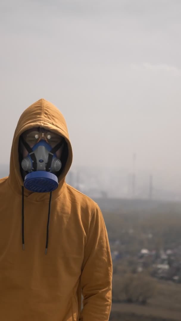 Vertikal. Mann mit Atemschutzmaske im Freien vor Smog-Hintergrund. Kopierraum — Stockvideo