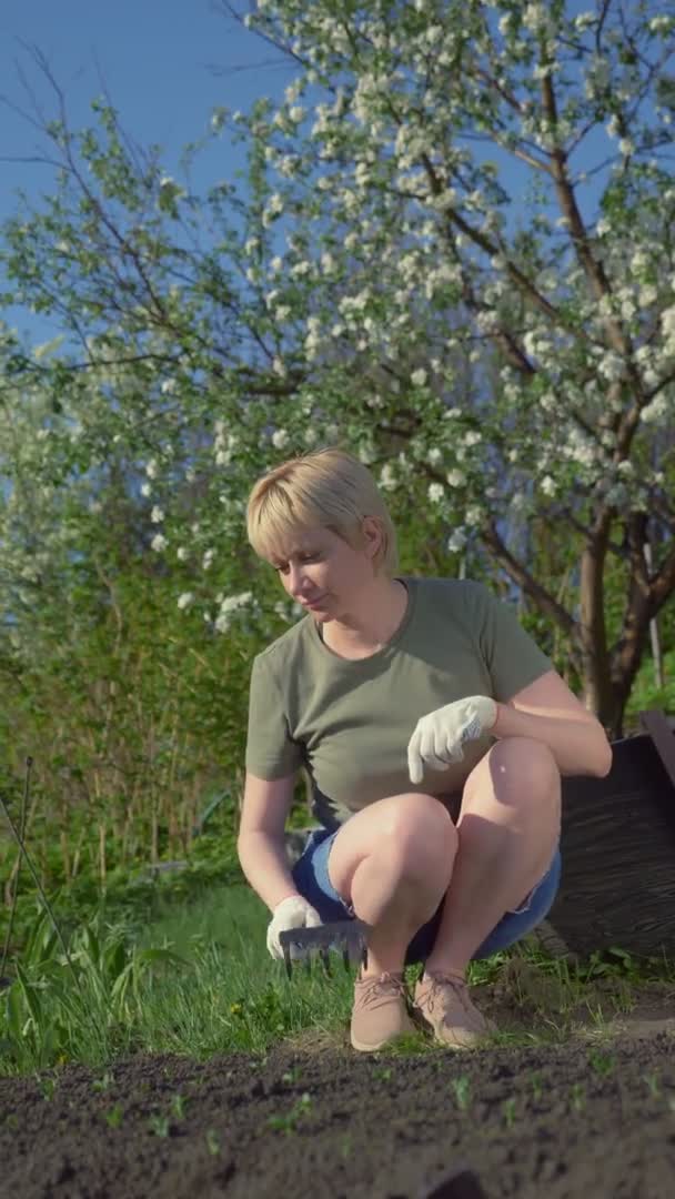 Verticalmente. joven hermosa mujer suelta las camas en el jardín. espacio de copia — Vídeos de Stock