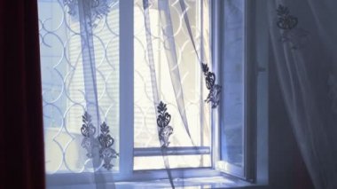 İşlenmiş demir ızgaralarla şeffaf pencere rüzgarla hafifçe hareket ediyor.