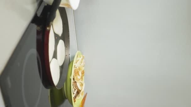 Verticaal. close-up, iemand kookt pannenkoeken in een pan op een fornuis aanraking — Stockvideo