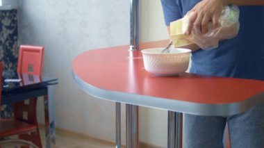 Bir adam un ile yumurta çırpar. Ev mutfağında tatlı yap.