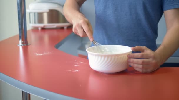 Чоловік б'є яйця з борошном. зробити десерт на домашній кухні — стокове відео