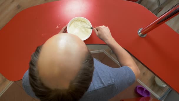 Ein Mann mit Glatze kocht zu Hause ein Dessert. Eier mit Mehl verquirlen — Stockvideo