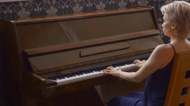 Zarif, kırılgan bir kadın evde piyano çalıyor.