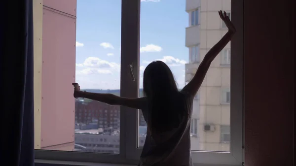 Silhouet. meisje wordt uitgerekt door het raam met uitzicht op de lucht en de bergen — Stockfoto
