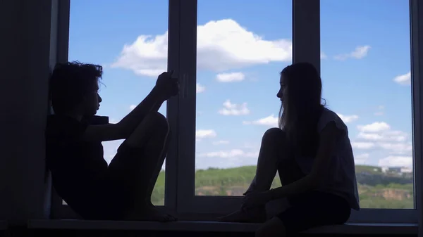Hermanos y hermanas adolescentes están sentados en el alféizar de la ventana. visto desde la ventana del cielo — Foto de Stock