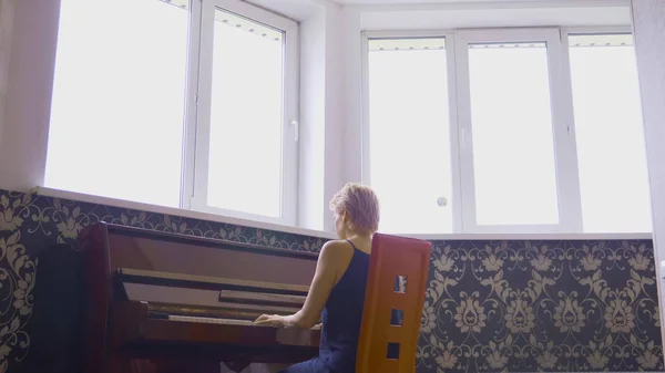 Mulher frágil elegante toca piano em casa na sala de estar — Fotografia de Stock