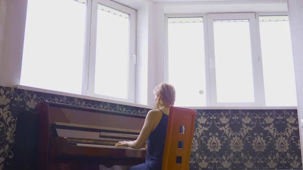 Mulher frágil elegante toca piano em casa na sala de estar — Fotografia de Stock