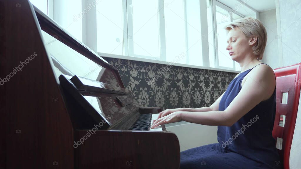 elegant fragile woman plays piano at home in the living room