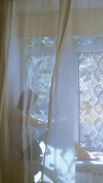Verticaal. tiener meisje zit op vensterbank en kijkt uit het raam. vervaging — Stockfoto