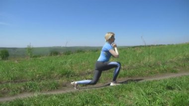İnce bir kadın spor için tepelerdeki bir tarlaya gider. hamleler yapar