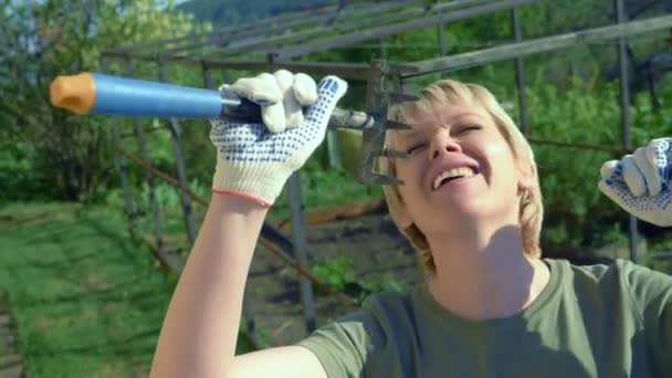 Beautiful young woman sings holding a rake like a microphone — Stock Video