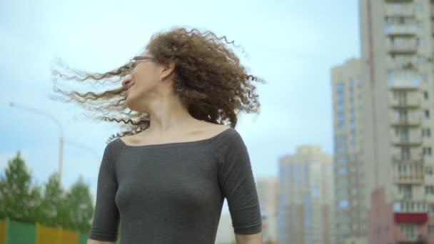 Mulher com cabelo encaracolado vira a cabeça na rua, o vento no cabelo — Vídeo de Stock