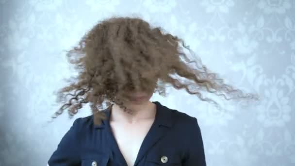 Glimlachende vrouw in bril met krullend haar wervelt haar hoofd, de wind in haar haar — Stockvideo