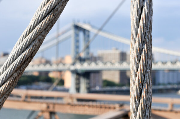 View of the NYC Skyline and the Manhattan Bridge from the Brooklyn Bridge in the summer.