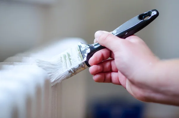 Close up van schilder arm schilderen van een radiator van de verwarming met een verfroller. Professional Workman Hand met vuile Paintbrush. — Stockfoto