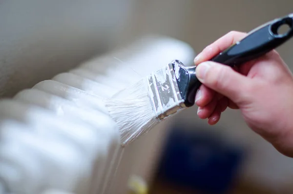 Close up van schilder arm schilderen van een radiator van de verwarming met een verfroller. Professional Workman Hand met vuile Paintbrush. — Stockfoto