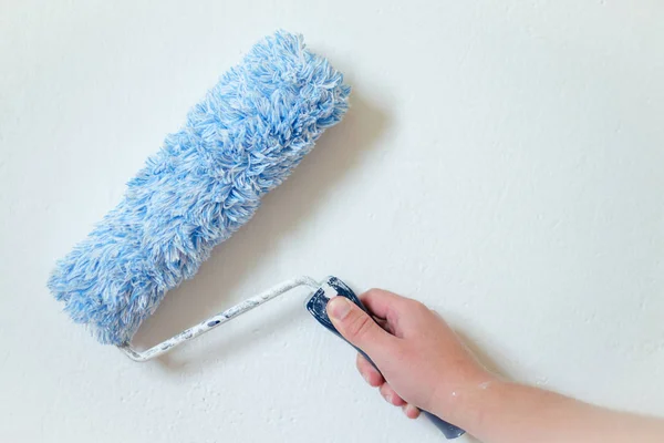 Fechar o braço do pintor pintando uma parede com rolo de pintura. Profissional trabalhador mão segurando rolo de pintura suja . — Fotografia de Stock