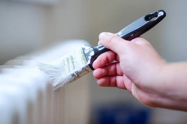 Close up van schilder arm schilderen van een radiator van de verwarming met een verfroller. Professional Workman Hand met vuile Paintbrush. — Stockfoto