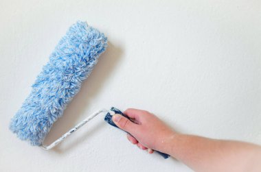 Bir duvar boya silindiri ile boyama ressam kolu kapatın. Profesyonel işçi el kirli boya silindiri tutarak.