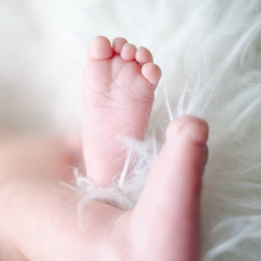 Bebek ayakları üzerinde beyaz kürk. Aile sevgisi kavramı. Yeni doğan Güzellik.