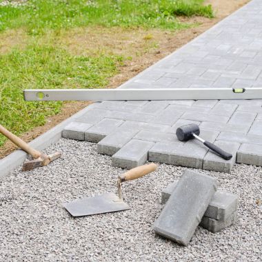 Stone blocks with tool for paving laying down background. Hausework architect concept clipart