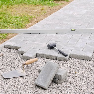Stone blocks with tool for paving laying down background. Hausework architect concept clipart