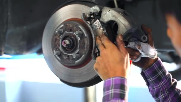 ガレージで車のリフトの下にディスク ブレーキを修理する自動車整備士 — ストック動画