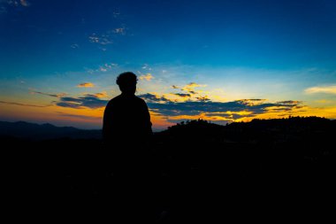 Siluet Mutlu Adam Tepe 'de Sunset on Mountain' da Blue Sky 'la duruyor. Huzurlu Anın tadını çıkarıyorum. Rahatlatıcı ya da başarı kavramı..