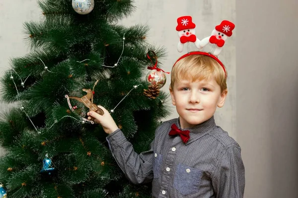 Mały chłopiec pozowanie z Boże Narodzenie akcesoria przed drzewa Xmas — Zdjęcie stockowe