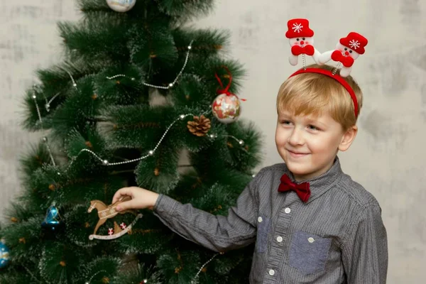 Mały chłopiec pozowanie z Boże Narodzenie akcesoria przed drzewa Xmas — Zdjęcie stockowe