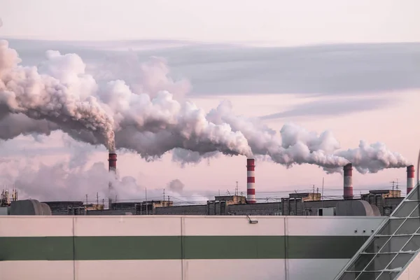 Industriella skorstenar med tung rök orsakar luftföroreningar som ekologiska problem på den rosa solnedgången himlen bakgrund Royaltyfria Stockbilder