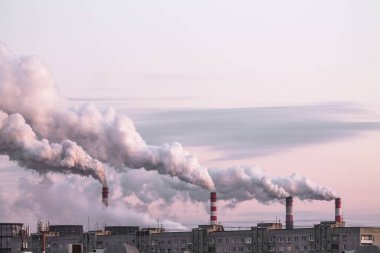 Yoğun dumanlı endüstriyel bacalar pembe günbatımı gökyüzü arka planında ekolojik sorun olarak hava kirliliğine neden oluyor