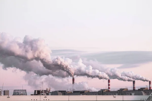 Chimeneas industriales con humo pesado que causan contaminación del aire como problema ecológico en el fondo rosado del cielo al atardecer —  Fotos de Stock