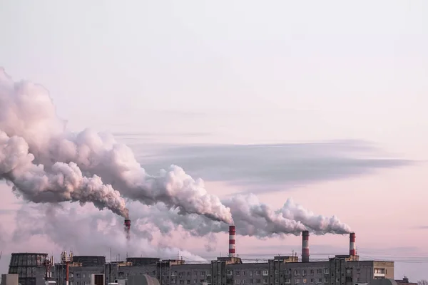 Chimeneas industriales con humo pesado que causan contaminación del aire como problema ecológico en el fondo rosado del cielo al atardecer —  Fotos de Stock