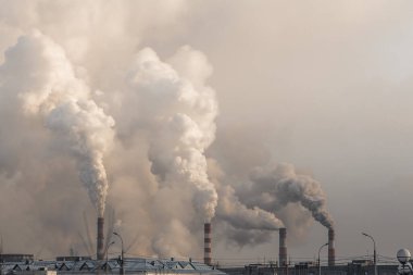 Ağır dumanlı sanayi bacaları gri gökyüzü arka planında hava kirliliğine yol açıyor