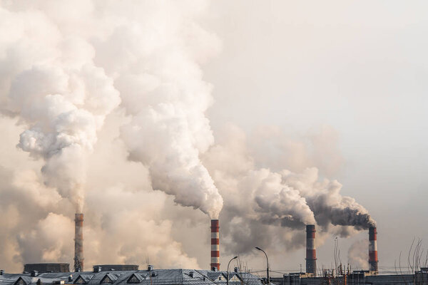 industrial chimneys with heavy smoke causing air pollution on gray sky background