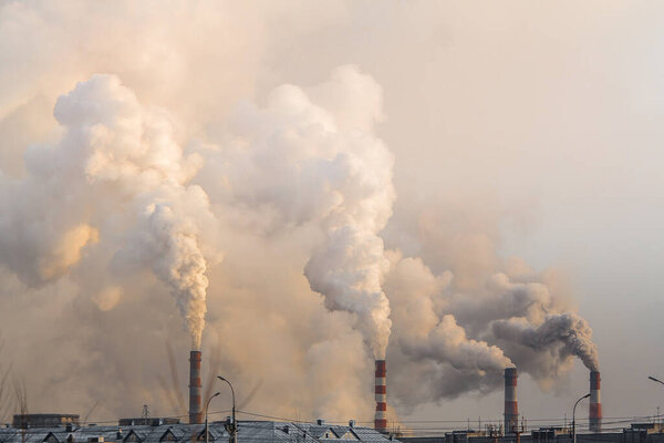 industrial chimneys with heavy smoke causing air pollution on gray sky background