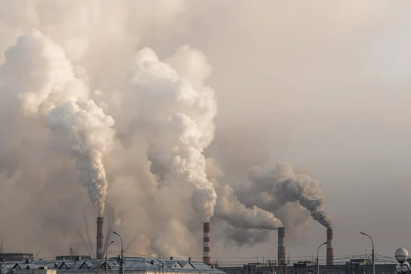 Industriële schoorstenen met zware rook die luchtverontreiniging veroorzaken op grijze lucht achtergrond — Stockfoto