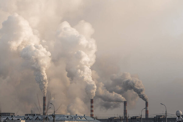 industrial chimneys with heavy smoke causing air pollution on gray sky background