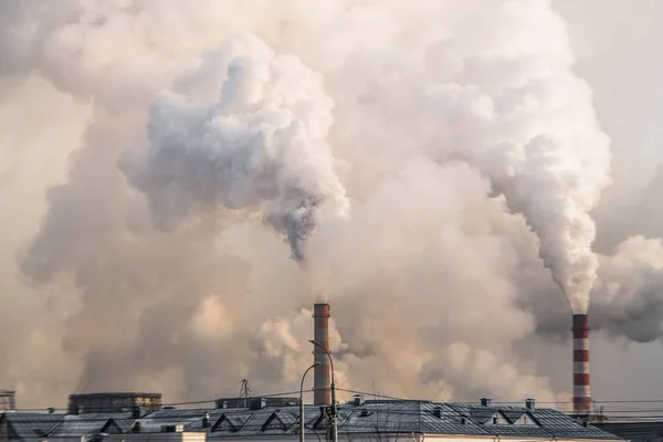 Industriella skorstenar med tung rök orsakar luftföroreningar på grå himmel bakgrund Stockfoto