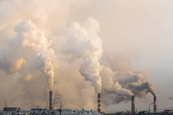Industriella skorstenar med tung rök orsakar luftföroreningar på grå himmel bakgrund Stockbild