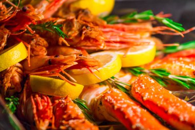 Bir sürü büyük pişmiş kırmızı karides, kral karidesleri, yengeç bacakları, limonlar ve biberiye dalları protein dolu sağlıklı bir yiyecek hediyesi.