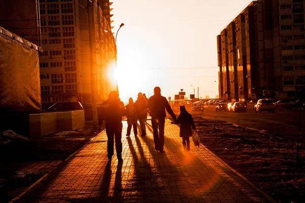 Calçada com pessoas caminhando depois do trabalho na luz traseira durante o pôr do sol — Fotografia de Stock