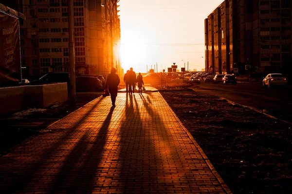 Calçada com pessoas caminhando depois do trabalho na luz traseira durante o pôr do sol — Fotografia de Stock